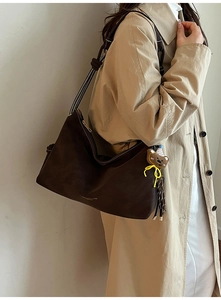 Detail der dunkelbraunen Wildleder-Tote Bag mit Kontrastnähten und Bärenanhänger