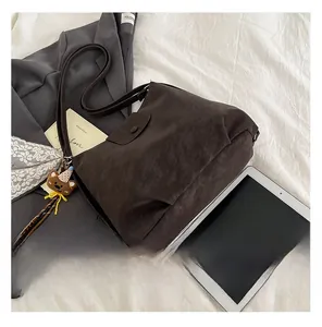 Detail of dark coffee textured leather tote bag with magnetic flap and cute bear pendant