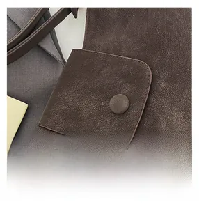 Close-up of brown leather tote bag detail with snap button and fine stitching texture