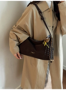 Detail der dunkelbraunen Leder-Shopper mit Kontrastnähten und Bären-Anhänger