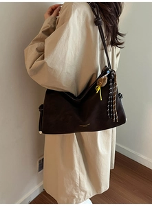 Detail einer dunkelbraunen Hobo-Tasche mit Knotengurten und langen Quasten-Verzierungen
