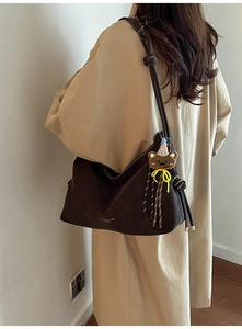 Detail der dunkelbraunen Leder-Shopper-Tasche mit Kontrastnaht und kleinem Bärenanhänger