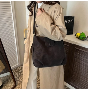 Detailed view of dark brown oversized tote bag worn with a classic beige trench coat