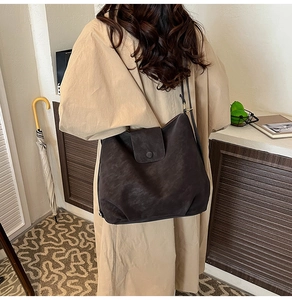 Detail view of large dark brown matte leather hobo bag worn by a model in home setting