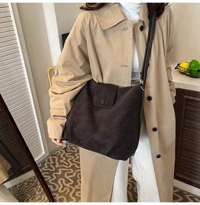 Macro shot of dark mocha suede tote bag with elegant flap and round decorative buckle