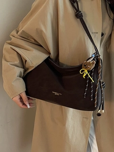Große braune Leder-Einkaufstasche mit Bärenanhänger, präsentiert am Modell im Mantel