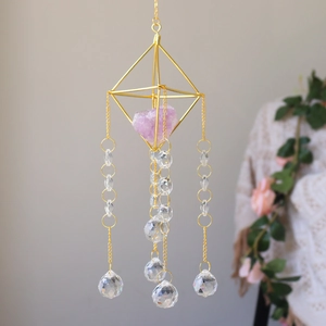 Macro detail of golden geometric frame with purple crystal and faceted suncatcher beads