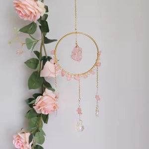 Bohemian suncatcher with pink crystals and golden metal ring hanging by pink roses