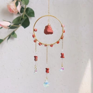 Detail of crystal suncatcher with gold ring, red raw stones and iridescent prisms