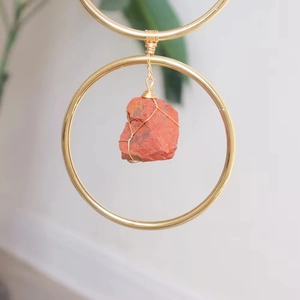 Detailed close-up of handmade wire-wrapped red crystal pendant in golden ring frame