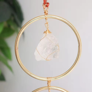 Detail of handmade crystal suncatcher with gold wire wrap and raw clear quartz