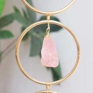 Macro shot of rose quartz crystal pendant with handmade wire wrapping in a gold frame