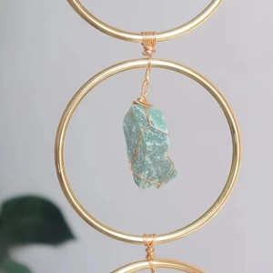 Detailed wire-wrapped natural green crystal stone within a golden circular tree of life ring