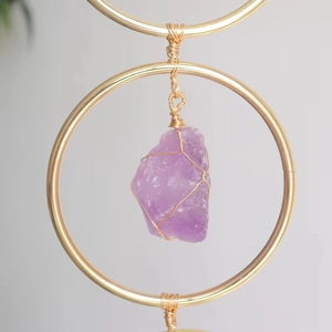 Macro shot of purple raw crystal pendant wrapped in gold wire inside a metal ring