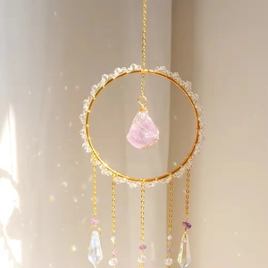 Macro detail of suncatcher ring with pink crystal and prism pendants reflecting rainbow light