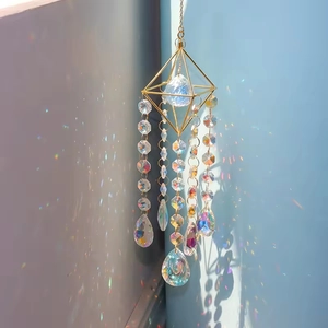 Close-up of crystal suncatcher with golden geometric frame creating rainbow light patterns