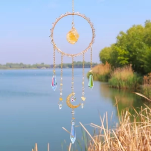 Golden suncatcher with citrine stone and crystal prisms hanging by a scenic lake