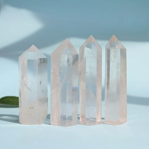 Rose quartz hexagonal crystal pillars set against a soft blue background