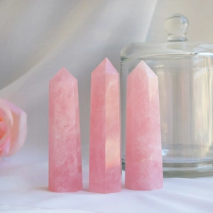 Set of three rose quartz hexagonal crystal points with natural textures on white silk