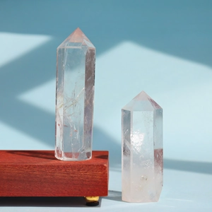 Polished white clear quartz hexagonal crystal towers on wooden base with soft shadows