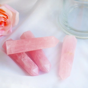 Polished rose quartz crystal points set on white silk with elegant flower petals