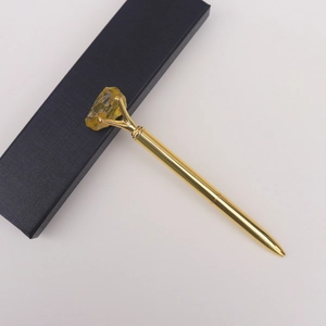 Stylo à bille doré en métal avec cristal jaune brut sur un coffret cadeau noir