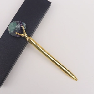 Détail d'un stylo à bille en métal doré avec cristal de fluorite brut et boîte cadeau
