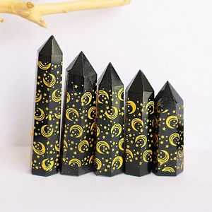 Detailed view of obsidian crystal points with gold star and moon engravings on black surface