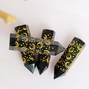 Obsidian hexagonal crystal prisms with gold moon and star patterns on white background