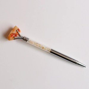 Détail d'un stylo à bille argenté avec éclats de cristal jaune et pierre brute