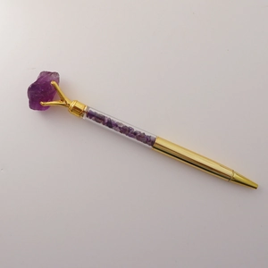 Detail of amethyst crystal ballpoint pen with gold metal trim and raw gemstone top