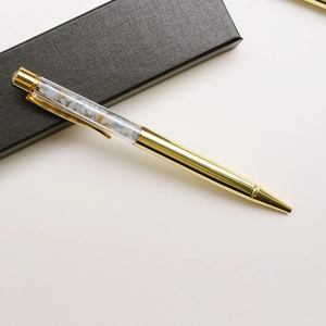 Detailed macro view of golden metal pen with light blue crushed crystal stones