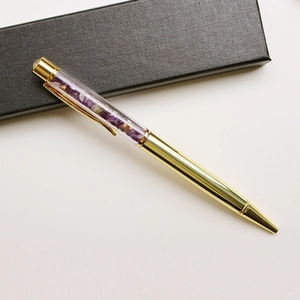 Detail of a gold metal ballpoint pen featuring purple crystal stones in a clear barrel
