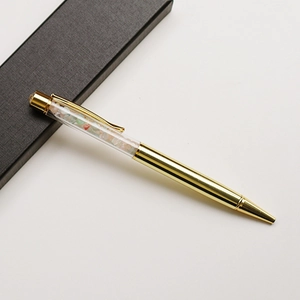 Close-up of golden metal ballpoint pen with colorful crystals in gift box