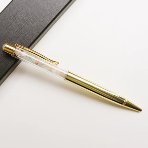 Close-up of golden metal ballpoint pen filled with colorful crystal crushed stones