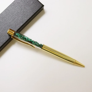 Golden crystal ballpoint pen with green stone details in a black textured gift box