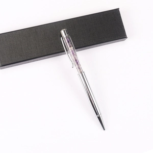 Silver ballpoint pen with purple crystals in window on a textured black gift box