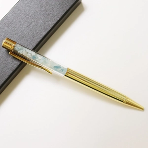Detail of a gold crystal pen with blue crushed stones inside a black textured gift box