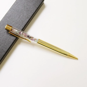 Detail of a golden crystal pen with crushed colorful gemstones in a black gift box
