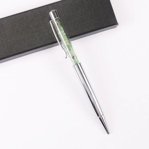 Detail of silver crystal ballpoint pen featuring green gemstone chips and black gift box