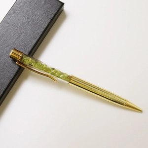 Detail view of golden crystal ballpoint pen with green gemstone filling and black gift box