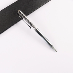 Macro detail of silver metal ballpoint pen featuring transparent crystal gravel top section