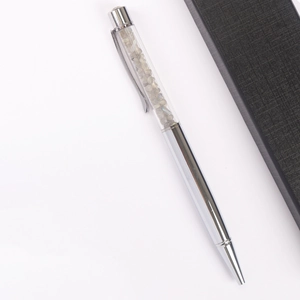 Silver ballpoint pen filled with grey crystal stones next to a black textured gift box