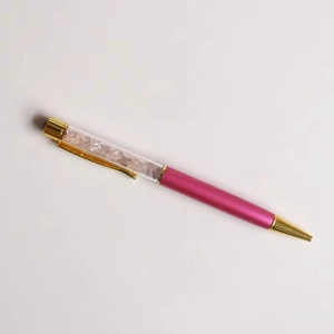 Close-up of pink crystal crushed stones inside a stylish rose pink and gold ballpoint pen
