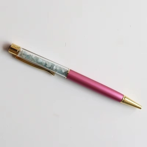 Close-up of rose pink crystal ballpoint pen with light blue stones and gold metal accents