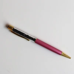 Detail of rose pink crystal ballpoint pen featuring decorative black gravel stones