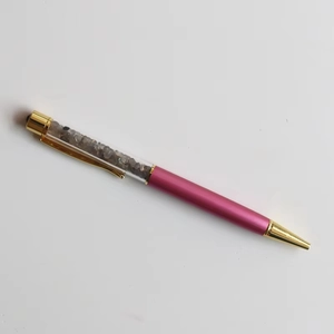 Macro detail of ballpoint pen with grey crystal stones inside a transparent barrel