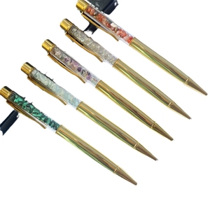 Set of 5 golden metal ballpoint pens with colorful crystal stone fillings on white background