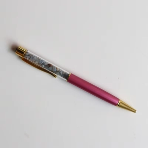 Detail of rose red crystal ballpoint pen with blue-grey gravel in clear barrel