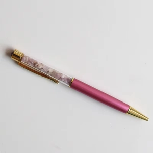 Detail of pink metal ballpoint pen with gold clip and purple crystal stones filling